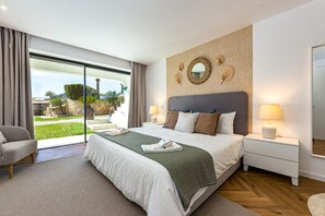 A modern bedroom with a large bed, a view of the outdoors, and a wooden wall with decorative mirrors.