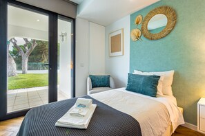 A modern bedroom with a large bed, a view of the outdoors, and a decorative mirror.