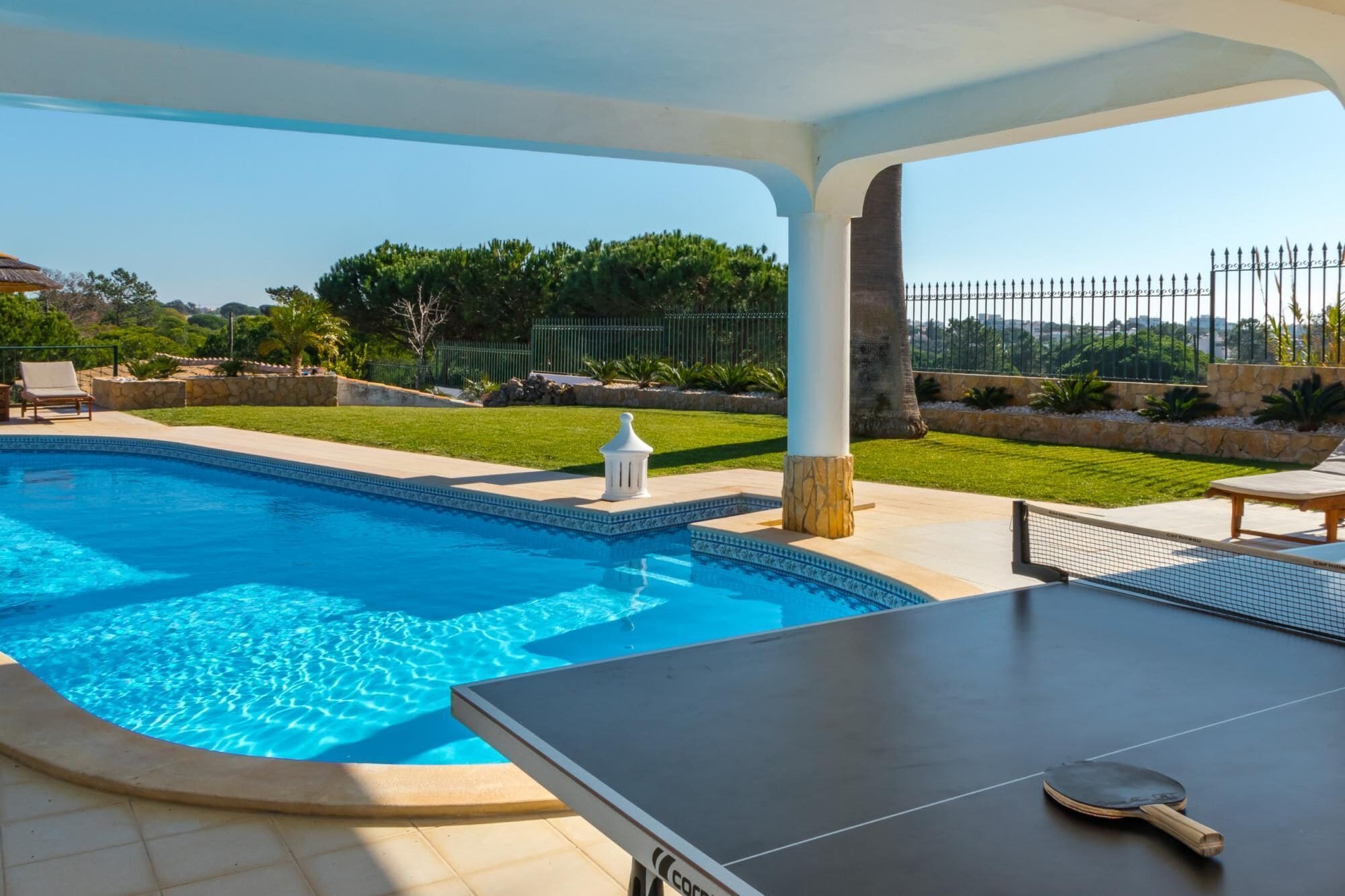 A swimming pool with a sun lounger and a ping pong table.