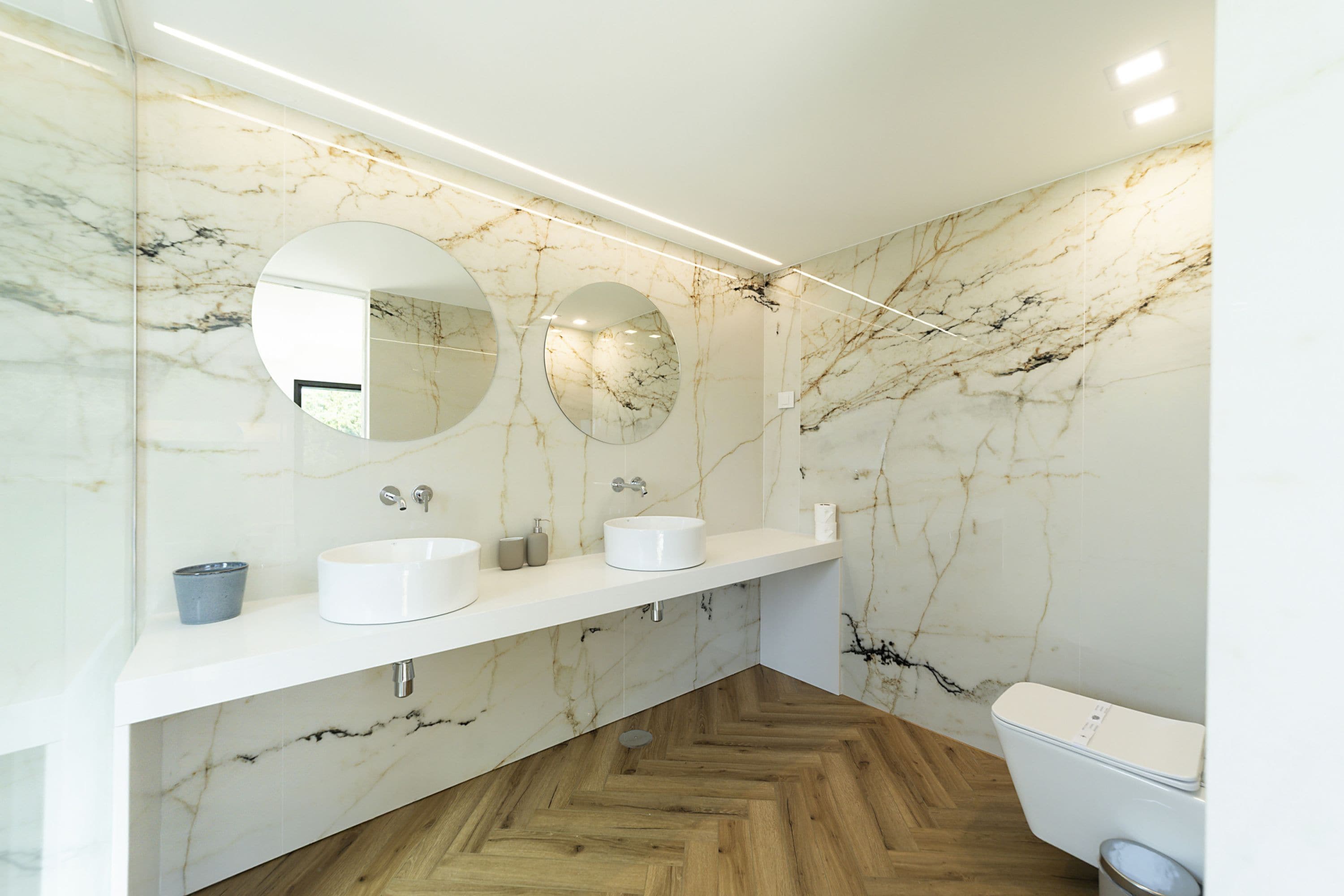 A bathroom with marble walls, two sinks, and a toilet.