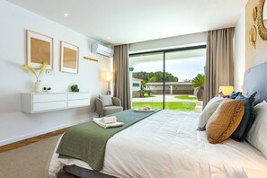 A modern hotel room with a large bed, a sofa, a desk, and a view of the garden. - Quintinha da Balaia in Albufeira (Albufeira)
