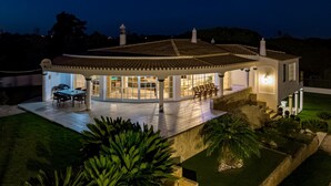 Une maison moderne dotée d’un patio couvert, d’un coin repas et d’un jardin bien entretenu.