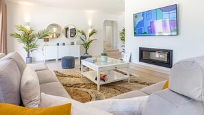 A modern living room with a sofa, coffee table, and a flat-screen TV mounted on the wall. - Casinha in Albufeira (Albufeira)