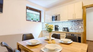 A dining area with a wooden table set for four, a microwave, and a coffee maker in the kitchen. - Harrachov Lhje260 in Harrachov (Harrachov)