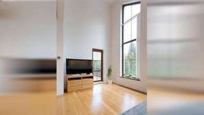 A spacious living room with a large window, a flat-screen TV, wooden flooring, and a grey rug. - Harrachov Lhje260 in Harrachov (Harrachov)