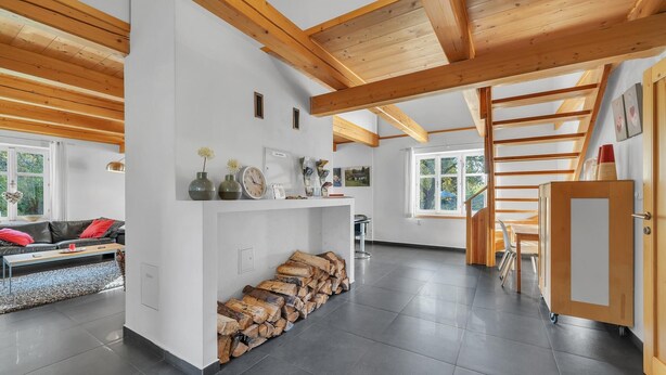 Un vaste espace de vie doté d’un plafond en bois, d’une cheminée, d’un canapé et d’un escalier menant à un niveau supérieur.