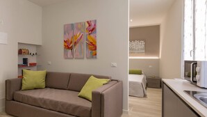 Un appartement moderne comprenant un canapé, un lit, un coin cuisine et une table à manger.