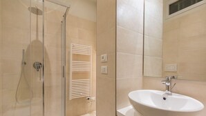 Une salle de bain moderne avec une douche à parois de verre, un lavabo blanc et un miroir.