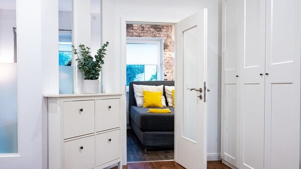 A bedroom with a bed, a white dresser, and a door leading to another room. - Shabby Chic Apartment in ideal Location (Hamburg)