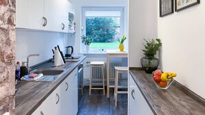 A compact kitchen with white cabinets, a wooden countertop, a window with a view of greenery, and a small dining area with stools. - Shabby Chic Apartment in ideal Location (Hamburg)