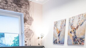 A bed with a grey textured bedspread, two yellow pillows, and a folded yellow towel. There are two wall-mounted paintings of deer. - Shabby Chic Apartment in ideal Location (Hamburg)