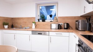 Una cocina moderna con armarios blancos, lavavajillas integrado, tostadora y cafetera.