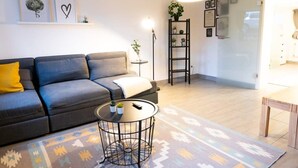 Una sala de estar moderna con un sofá gris, una mesa de centro redonda y un tapete estampado.