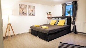 Un dormitorio con una cama, una lámpara de pie y dos cuadros en la pared.