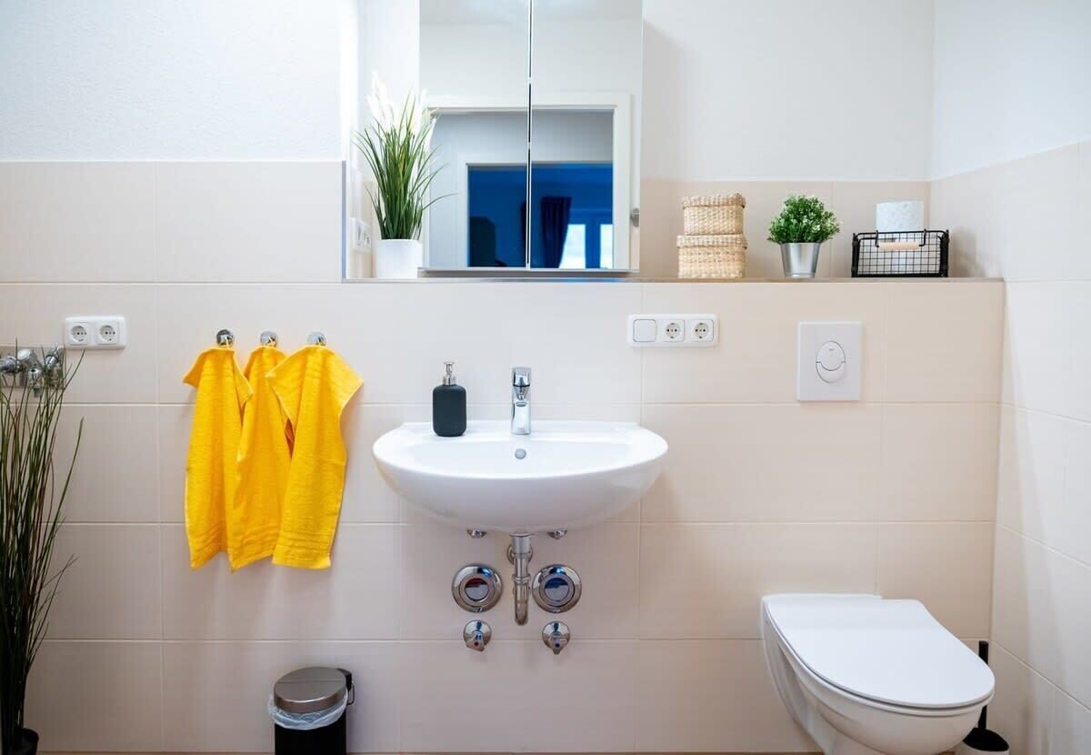 Une salle de bain avec un lavabo blanc, des toilettes et des serviettes jaunes accrochées au mur.