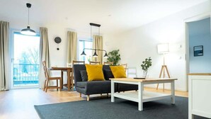 Een moderne woonkamer met een bank, salontafel en eethoek.