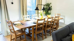 Een eethoek met een houten tafel en stoelen, een vaas met bloemen en een plant op tafel.