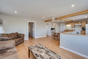 A spacious living area with a sofa, a coffee table, and a kitchen area with wooden cabinets and a dining table.