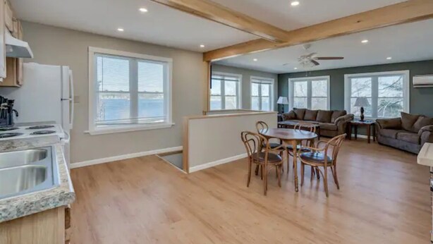 A spacious living area with a dining table, chairs, a sofa, and a kitchen area with a stove and sink.