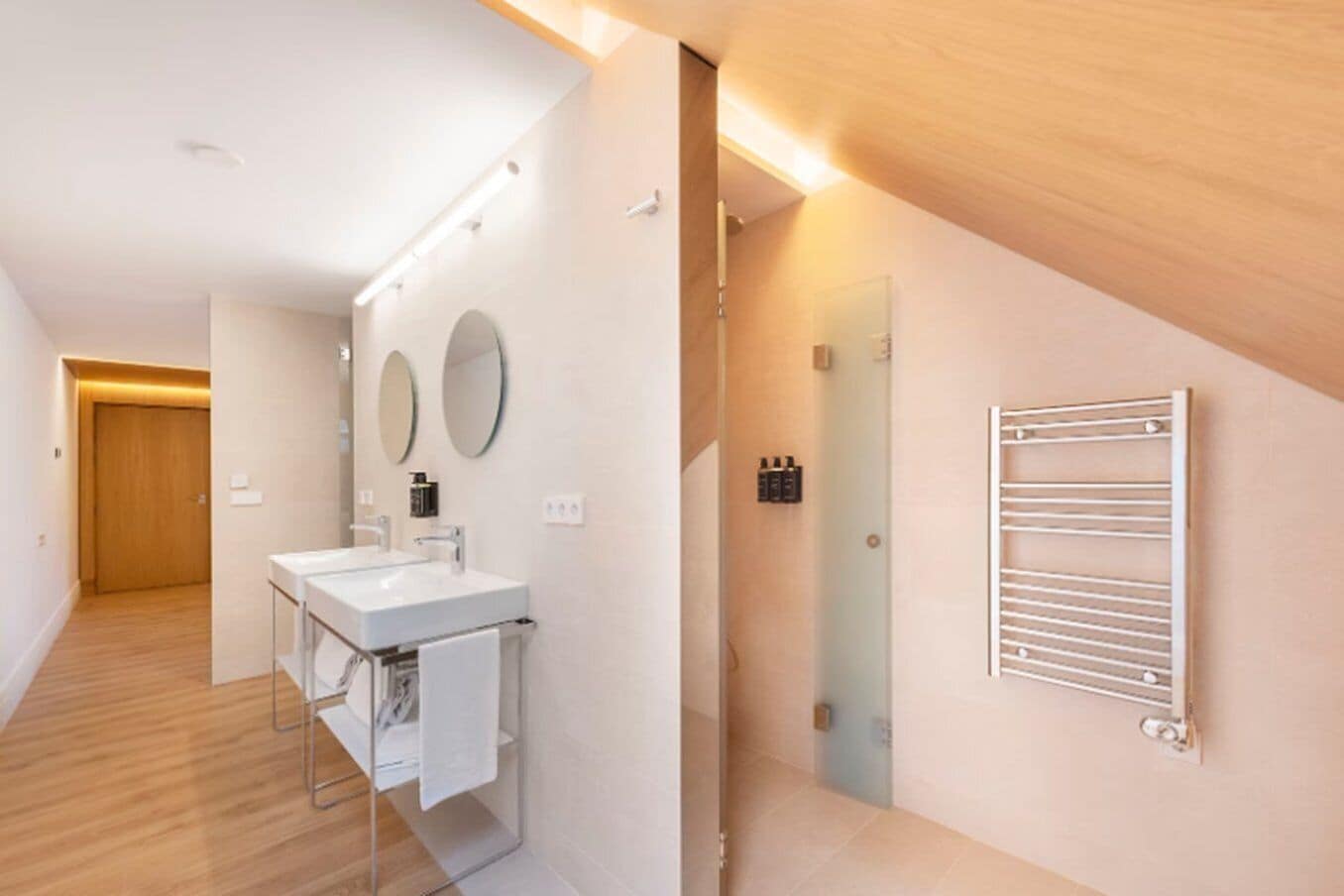 A modern bathroom with a large mirror, a sink, and a towel rack.