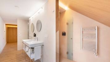 A modern bathroom with a large mirror, a sink, and a towel rack.