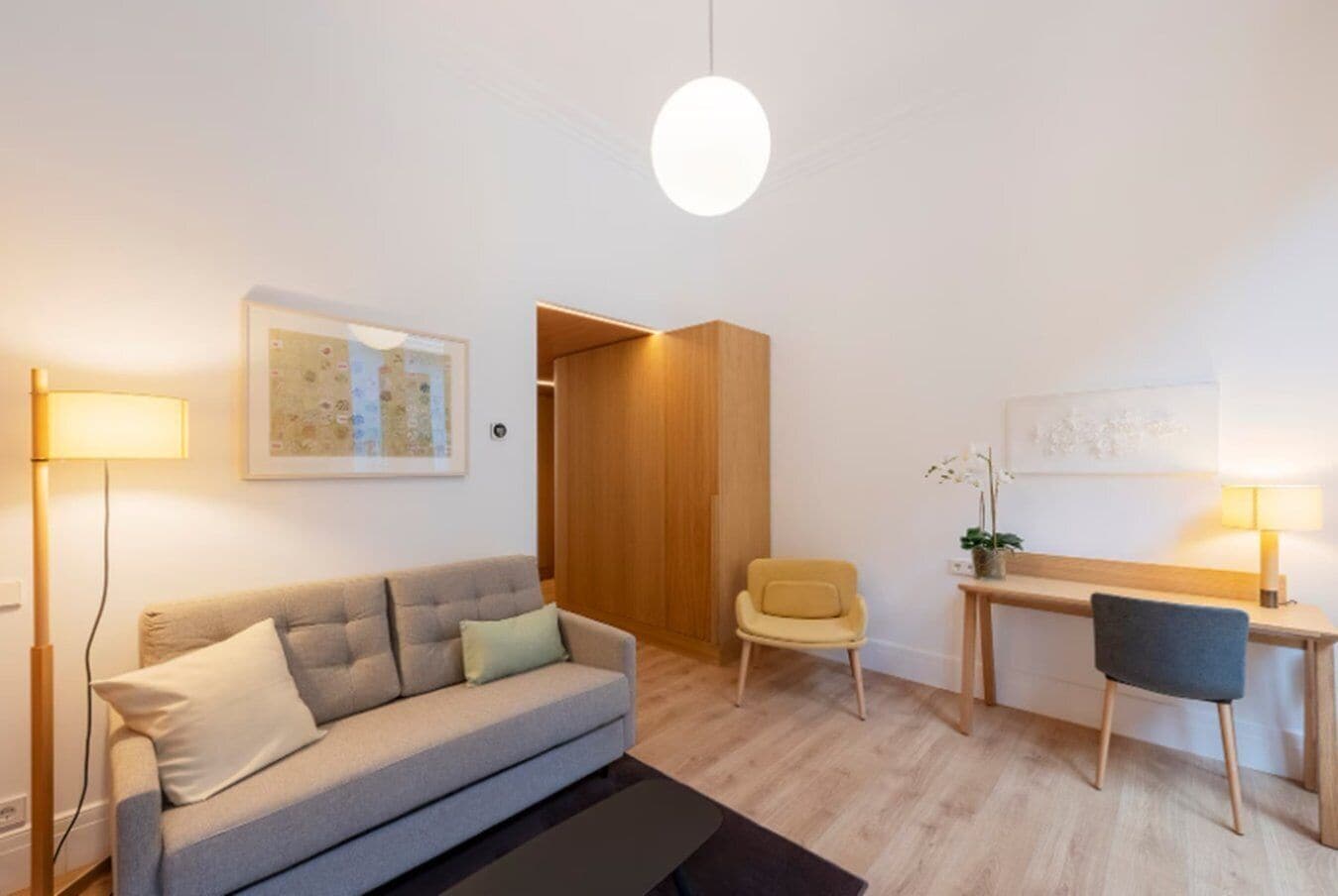 Una sala de estar moderna con un sofá, una silla, un escritorio y una lámpara colgante.