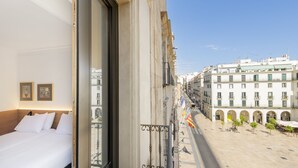 Habitación de hotel con balcón que da a una calle de la ciudad y un patio.