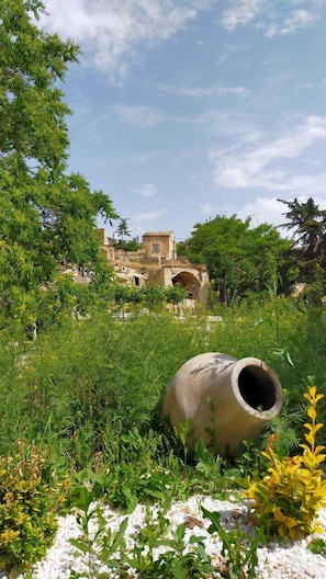 An ancient ruin with stone structures and a large pottery vessel in a grassy area. - Cappadocia Deep Cave House (Ürgüp)