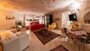 Ein gemütliches Zimmer mit Bett, Sofa, Esstisch und Fernseher.