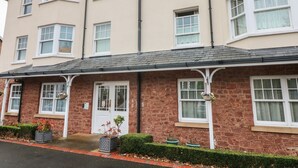 A multi-story residential building with a stone facade, multiple windows, and a front door with a small porch area. - 1 Tregonwell Court (Minehead)