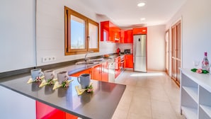 A modern kitchen with a central island, stainless steel appliances, and bright red cabinets. - Finca in Mallorca El Rafal de Son Alberti with pool (Buger)