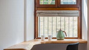 A corner desk with a wooden surface, a green kettle, two white cups, and a black chair. - Design Rooms Verona (Verona)