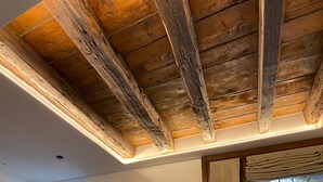 A room with exposed wooden beams, a large window with a view of a cityscape, and a painting on the wall. - Design Rooms Verona (Verona)