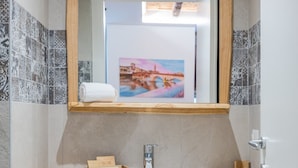 A bathroom with a wooden vanity, a white sink, a mirror, and a framed picture on the wall. - Design Rooms Verona (Verona)