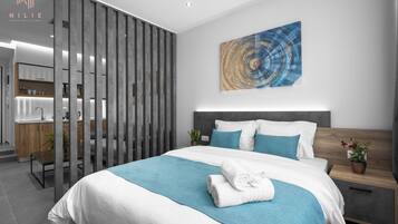 Ein modernes Hotelzimmer mit einem großen Bett, einem Holfnachtkästchen, einer Topfpflanze und einem Wandbild.