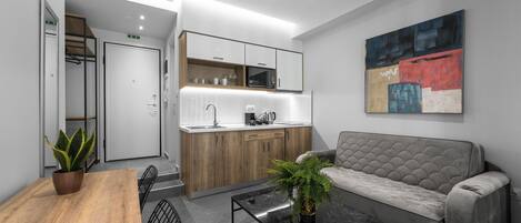 Une cuisine moderne équipée d’un four à micro-ondes, d’un évier et de meubles en bois. On y trouve également un canapé et une table basse agrémentée d’une plante.