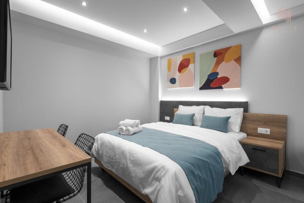 Una habitación de hotel moderna con una cama bien hecha, una mesa de madera y una silla.