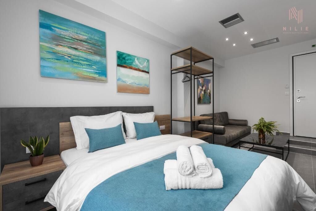 A modern hotel room with a bed, a seating area, and artwork on the walls.