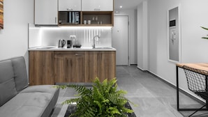 A modern kitchen with wooden cabinets, a grey sofa, and a small dining table. - Factory Inn Nilie Hospitality MGMT (Thessaloniki)