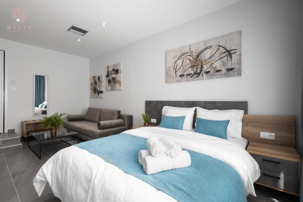 A modern hotel room with a large bed, a sofa, a coffee table, and artwork on the walls.
