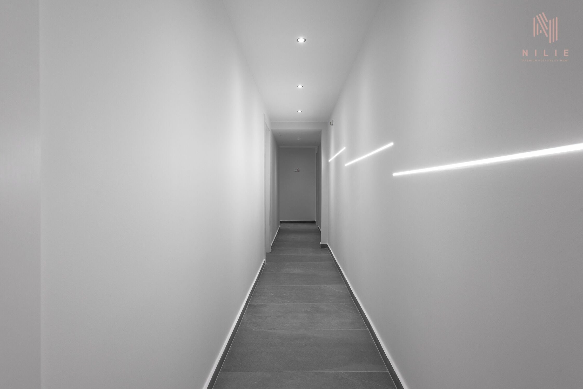 En smal, modern hall med infälld belysning och ett enkelt golv.