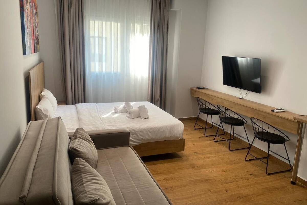 Une chambre d’hôtel moderne dotée d’un grand lit, d’un canapé, d’un bureau avec des chaises et d’un téléviseur à écran plat.