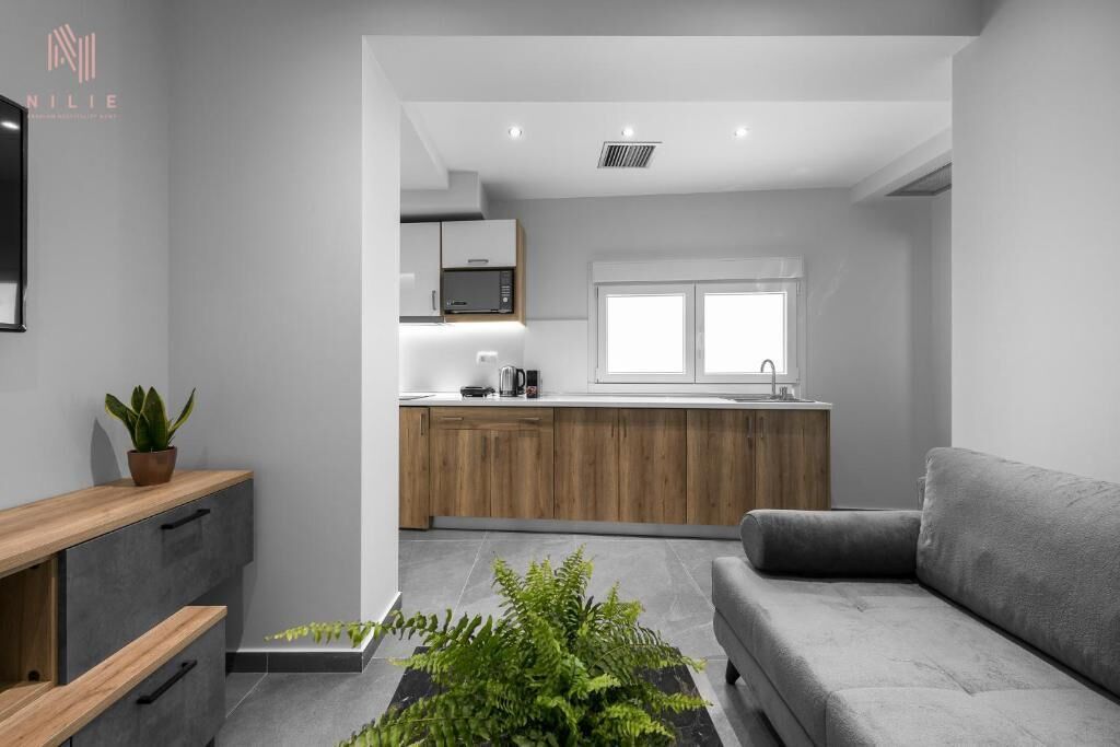 A modern kitchen with wooden cabinets, a microwave, and a window above the sink.