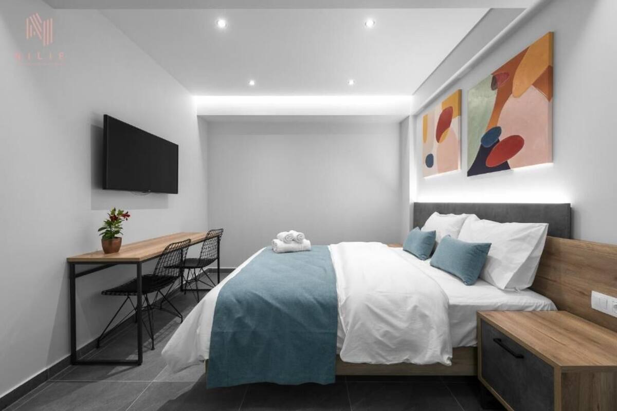 Une chambre d’hôtel moderne équipée d’un lit, d’une table de chevet, d’un bureau, d’une chaise et d’un téléviseur à écran plat.