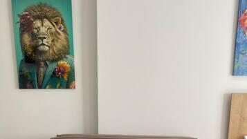 A beige sofa with two cushions, a teal painting of a lion, and a wooden headboard.