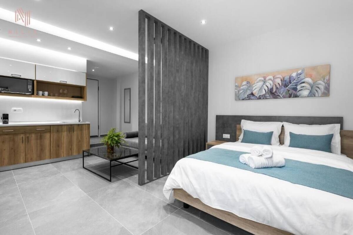 Une chambre d’hôtel moderne avec un grand lit, un bureau en bois et une kitchenette.