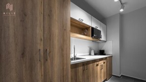 A modern kitchen with wooden cabinets, a white countertop, and a built-in oven. - Factory Inn Nilie Hospitality MGMT (Thessaloniki)