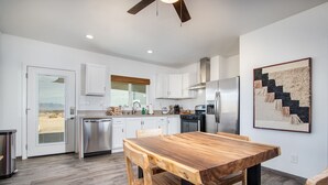 Una cocina moderna con armarios blancos, electrodomésticos de acero inoxidable y una mesa de comedor de madera.
