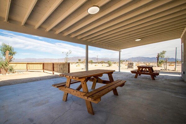 An outdoor covered patio with picnic tables and a view of mountains. - Private Hot Springs - Desert Willow House (Twentynine Palms)