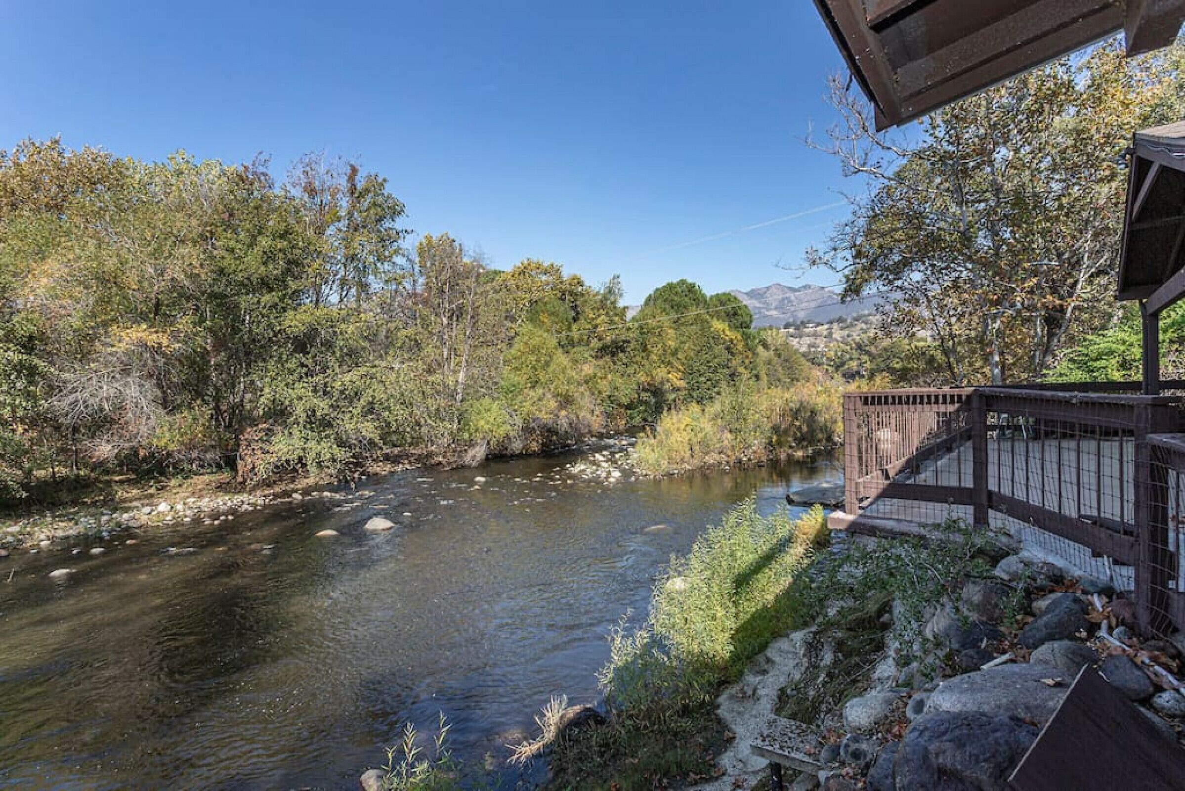Un fiume con un ponte di legno e un edificio con una recinzione.